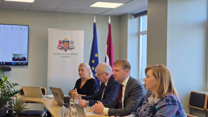 Sanāksmju telpa, pie galda sēž klimata un enerģētikas ministrs ar citiem ministrijas darbiniekiem