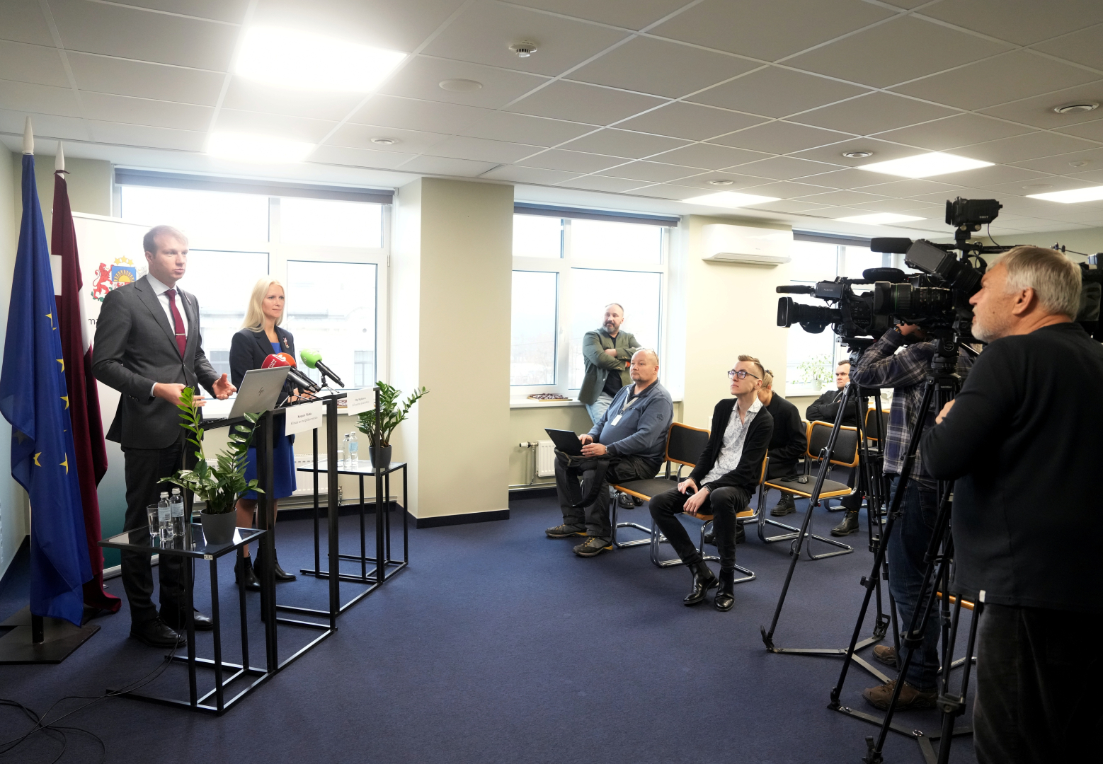 Zāle ar mediju pārstāvjiem, kas klausās preses konferenci