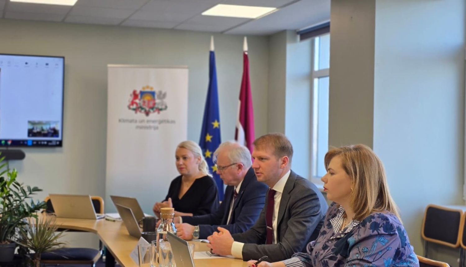 Sanāksmju telpa, pie galda sēž klimata un enerģētikas ministrs ar citiem ministrijas darbiniekiem